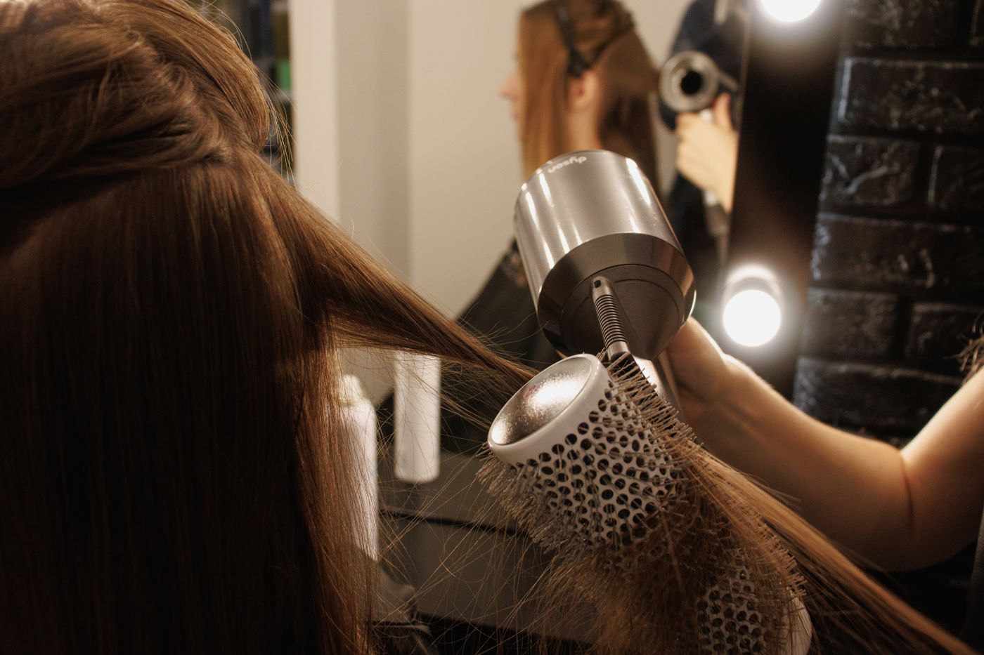 A stylist shaping long hair with a brush and hairdryer