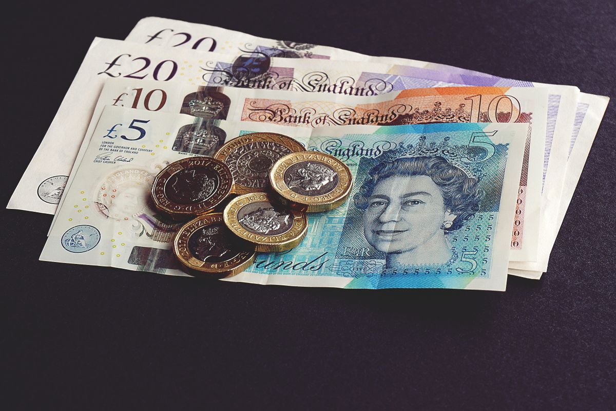 British pound notes and coins arranged on a dark surface
